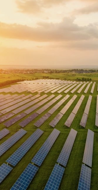 Aerial view of large electrical power plant with many rows of solar photovoltaic panels for producing clean ecological electric energy in morning. Renewable electricity with zero emission concept.